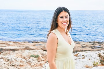 Fototapeta na wymiar Young beautiful woman smiling happy. Standing with smile on face looking at the camera at the beach