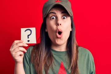 Beautiful woman wearing cap with red star communist symbol holding question mark reminder scared and amazed with open mouth for surprise, disbelief face