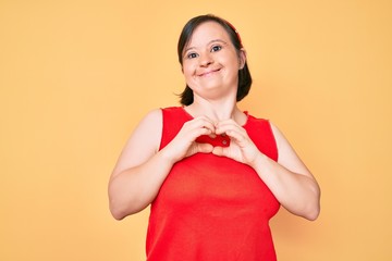 Brunette woman with down syndrome wearing casual clothes smiling in love showing heart symbol and shape with hands. romantic concept.