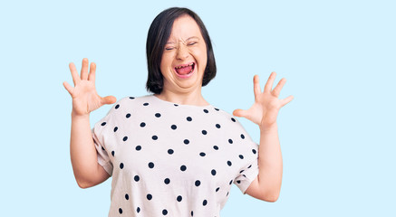 Fototapeta na wymiar Brunette woman with down syndrome wearing casual clothes celebrating mad and crazy for success with arms raised and closed eyes screaming excited. winner concept