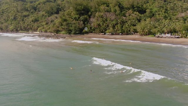 Aerial drone view of surfers riding ocean waves in Philippines, circle pan, day