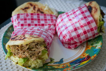 Corn arepas stuffed with beef, chicken breast, pork ham, mozzarella cheese and avocado.corn arepa with sausages, sausage meat. pork sausage, grilled sausages. 
