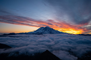 Panoramic view of Mount Rainier above the clouds during the sunrise with dramatic color in the sky