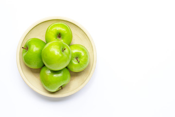 Fresh green apples on pottery plate on white background.