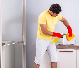 Young handsome man cleaning in the bedroom