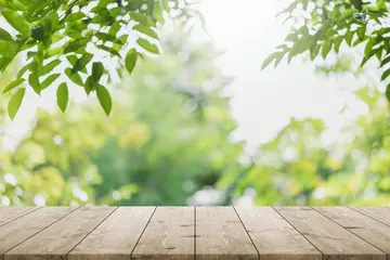 Fotobehang Tuin Leeg houten tafelblad en wazige groene boom op de achtergrond van de parktuin - kan worden gebruikt voor het weergeven of monteren van uw producten.