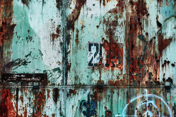 Grange metal wall with dull turquoise paint, rust, hunting target, bullet holes and number 203. Abandoned military hangar from Russia - ideal background for website about urban exploration