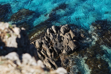 Fototapeta na wymiar Dark blue sea with rocks, view from above. Beautiful background with wild tropical sea beach.