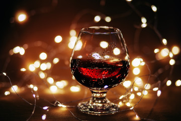 Glass with red wine, backlight, bokeh and blurry orange background.