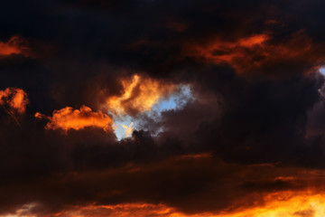 Hot flaming summer sunset. Sunset sky in red-orange tones. Dark storm clouds 
