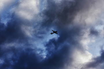 A sunset sky with clouds and a flying airplane.