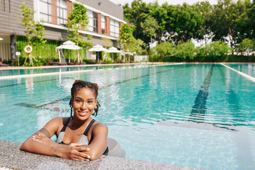 Portrait of beautiful young woman refreshing in swimming pool of spa resort on hot sunnyday