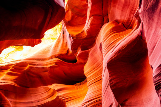 Natural red-orange sandstones stacked in layered fire waves in a narrow sandy labyrinth in Lower Antelope Canyon in Page Arizona
