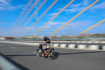 panning photo focus woman and kid use motocycle on the road and bridge