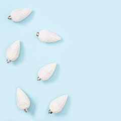 White Christmas toys in shape of pine cones, New Year toys on blue background.