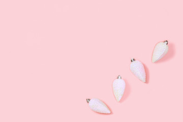 Christmas holidays background with white toys in shape of pine cones on millennial pink paper with copy space.