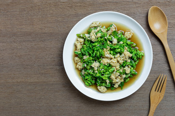 top view of stir fried cowslip creeper with egg in a ceramic dish on wooden table. homemade style healthy food concept.