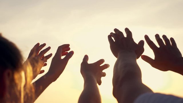 People's hands reach for the sun at sunset. Happy family together. Teamwork. A cry for help, People together in prayer turn to the sun.