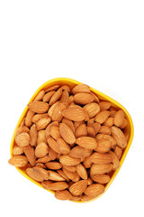 Group of almonds inside and outside bowl isolated on white.