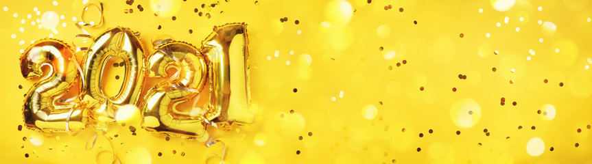 Golden foil balloons made numbers 2021 on yellow background with light bokehs. Banner, copy space. Happy new year celebration party. Greetings and congratulation concept
