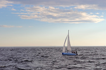 Naklejka na ściany i meble A sailing boat sails on the sea. Open sails. Active sport. Sailing on a yacht.