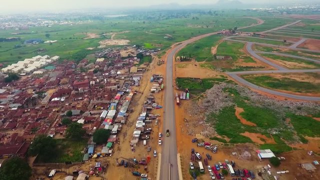 Aerial of road besides town with orange dirt and green grass