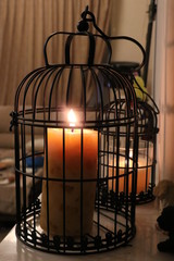 Fototapeta na wymiar Lighted candle in a black cage