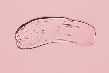 Transparent liquid gel on pink background. Textured smear with oxygen bubbles