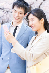 スマホを見るビジネスマンとＯＬ