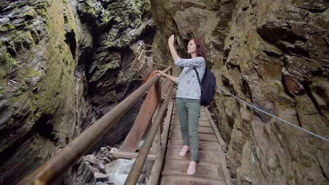 tourist taking photos while walking in a mountain gorge