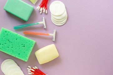Flat lay of bath and hygiene products. Razors, soap bars and washcloth on a lilac background. Space for text