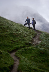 Obraz premium Full length of young woman and boyfriend standing on hillside path and holding hands. Loving couple hiking together in mountains. Concept of hiking, traveling and relationships.
