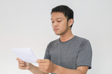 Young Asian man is reading the white paper mail message or the bill.