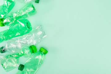 Top view of crumpled plastic bottles on green background with copy space, ecology concept