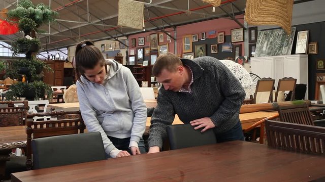 Happy adult couple visiting furniture store in search of table for home 