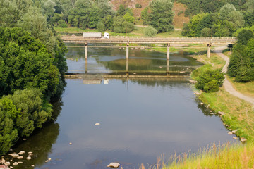 Concrete road bridge across the river flowing in deep valley