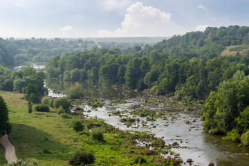 Fototapeta na wymiar River section with rapids and stones outcrops, forested hilly banks