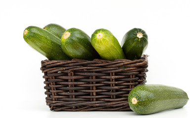 Fresh green zucchini in a wicker box on a white background