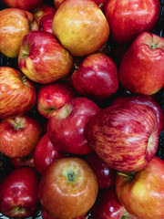 Red ripe apples lie in a heap on top of each other.