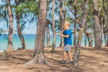 Camping people outdoor lifestyle tourists in summer forest near lazur sea. Blond serious boy in...