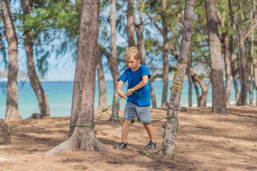 Camping people outdoor lifestyle tourists in summer forest near lazur sea. Blond serious boy in...