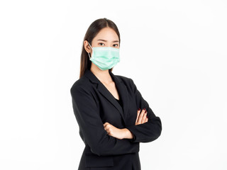 A confident beautiful young Asian business woman wearing green medical face mask and black suit, standing with her arms folded.