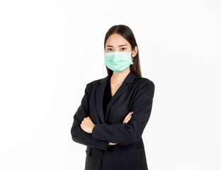 A confident beautiful young Asian business woman wearing green medical face mask and black suit, standing with her arms folded.