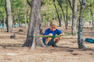 Camping people outdoor lifestyle tourists in summer forest near lazur sea. Blond serious boy in...