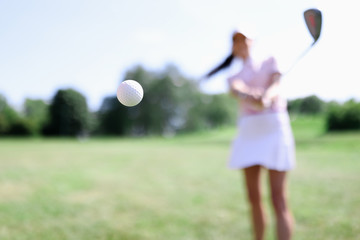 Golf ball against background of hitting woman closeup. Active healthy lifestyle concept