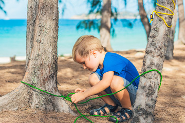 Camping people outdoor lifestyle tourists in summer forest near lazur sea. Blond serious boy in...