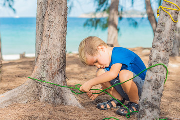 Camping people outdoor lifestyle tourists in summer forest near lazur sea. Blond serious boy in...