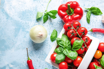Basket with fresh cherry tomatoes, herbs and spices on table