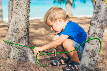Camping people outdoor lifestyle tourists in summer forest near lazur sea. Blond serious boy in...