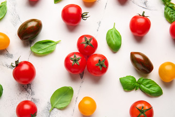 Fresh cherry tomatoes and basil on light background
